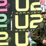 An Italian peacekeeper holds his rifle as he stands in front of wall covered with U2 posters in cent..